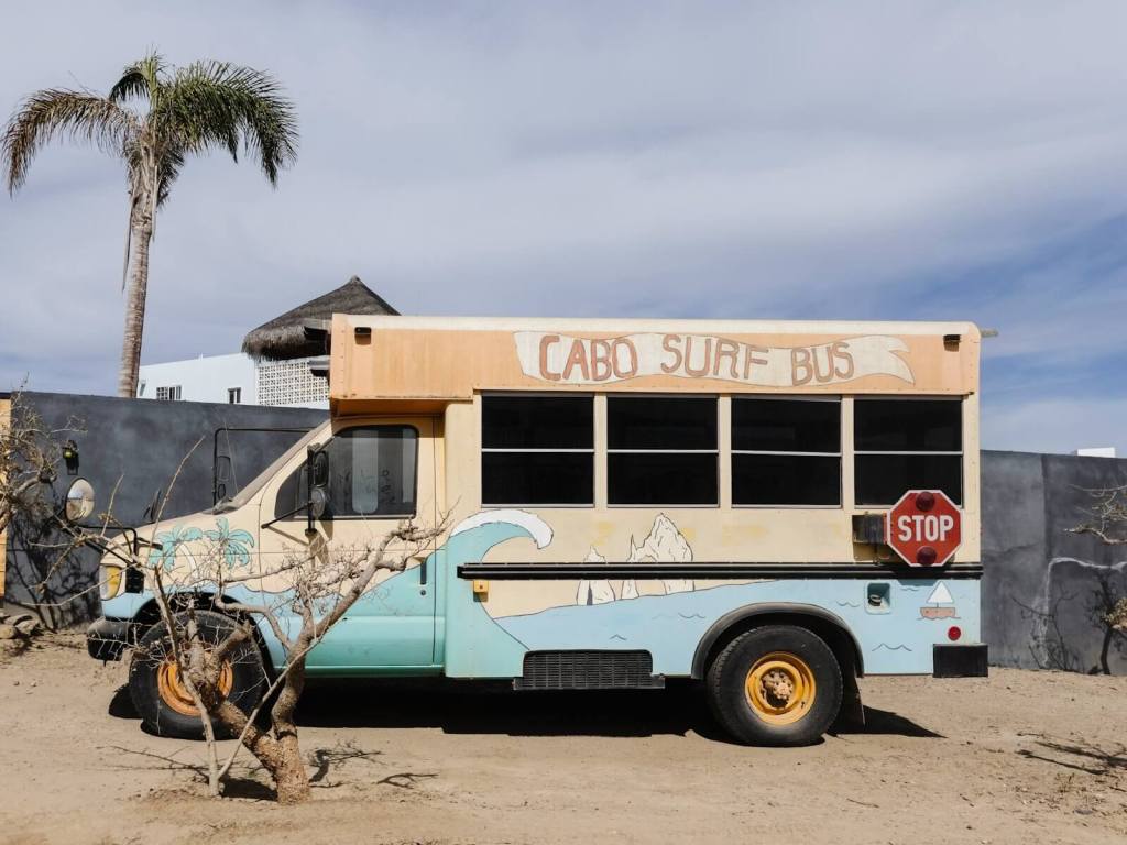 a blue and white bus parked on a dirt road